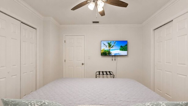 A bedroom with a bed, pillows, a TV on the wall, and a ceiling fan. - Comfy Home 4 Beds Steps to Hard Rock Stadium Free Parking Miami Gardens (Miami)