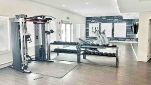 Une salle de sport équipée de matériel d’exercice, d’un miroir et d’un mur orné de citations motivantes.