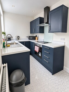 A modern kitchen with dark cabinetry, a stainless steel sink, and a built-in oven.