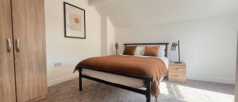 Une chambre à coucher avec un lit, une armoire, une table de chevet et une lampe.