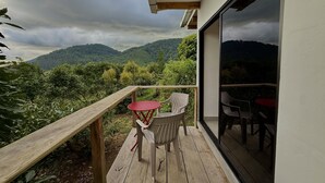 A wooden deck with a table and chairs, overlooking a mountainous landscape.