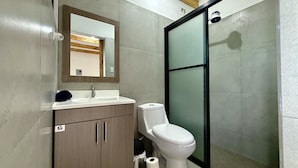 A bathroom with a toilet, sink, and mirror.