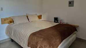 A bed with a wooden headboard, a brown blanket, and a white quilted bedspread.