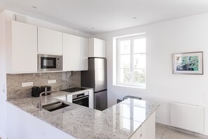 Eine moderne Küche mit weißen Schränken, Edelstahlgeräten, einer Granit Arbeitsplatte und einem Fenster für natürliches Licht.