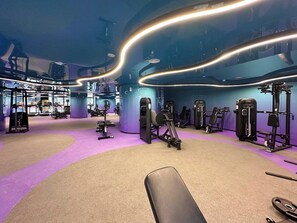 A gym with exercise equipment, a bench, and a purple carpet. - Brand-New 1BR in Neva Residence | Near Circle Mall (Dubai)