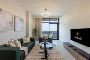 A modern living room with a sofa, coffee table, and a flat-screen TV. - Brand-New 1BR in Neva Residence | Near Circle Mall (Dubai)