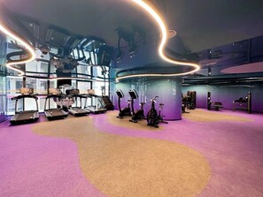 Une salle de sport équipée de tapis de course, de vélos d’appartement et d’appareils de musculation elliptique.