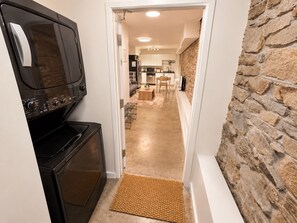 A kitchen with a black stove, a microwave, and a stone wall. - Modern Loft-Style Basement Bright & Spacious (Toronto)