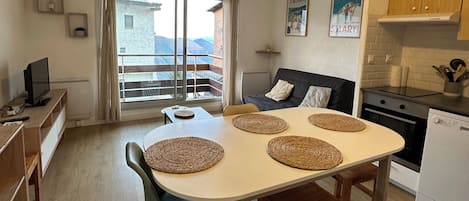 Una cuina moderna amb taula de menjador, cadires i vista a les muntanyes per la finestra.