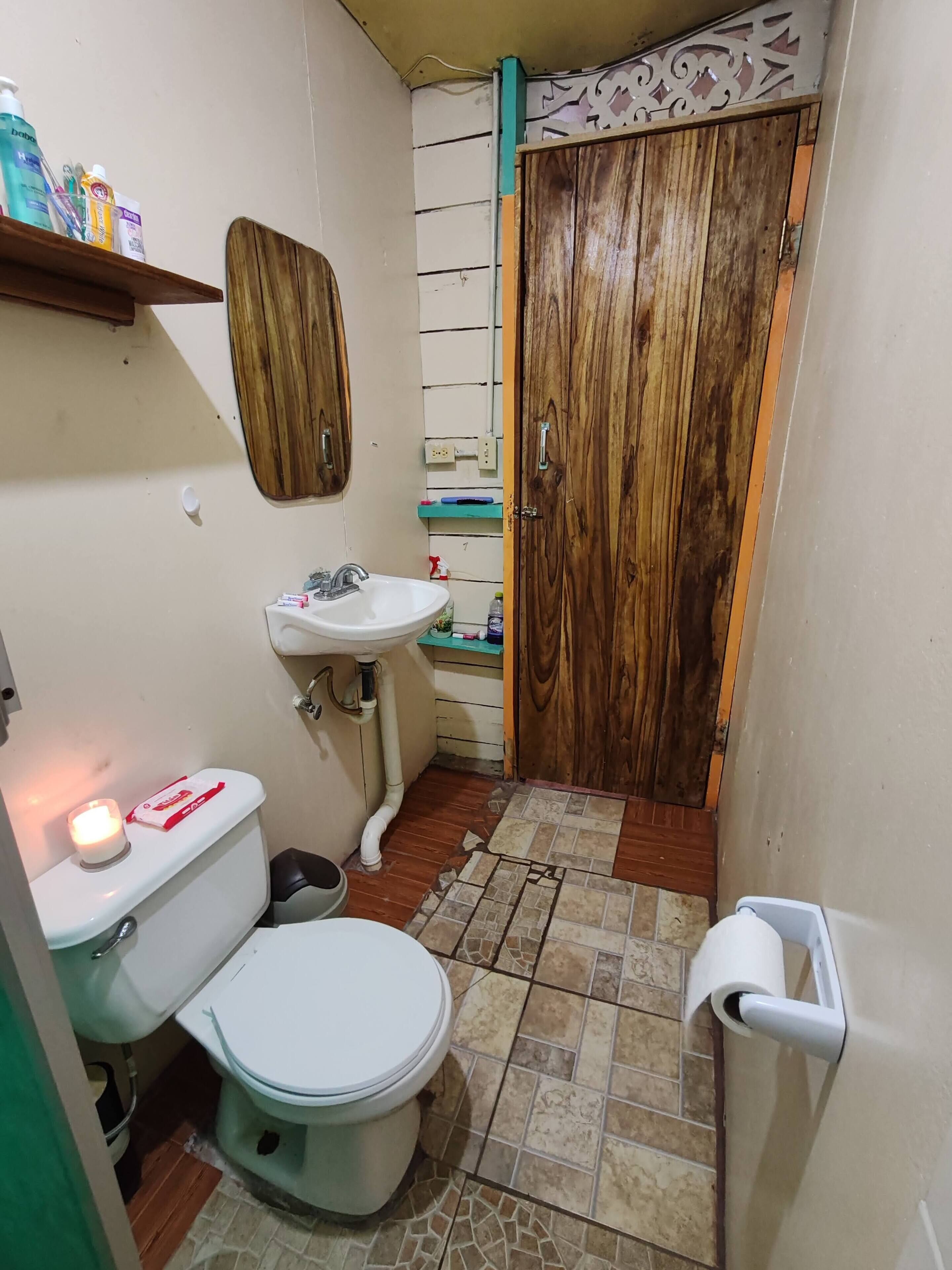 Un baño pequeño con inodoro, lavabo y una puerta de madera.
