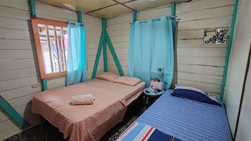 Una habitación con dos camas, una mesita y una ventana con cortinas.