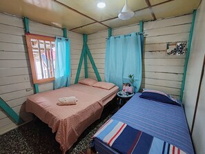 Una habitación con dos camas, una mesita y una ventana con cortinas.