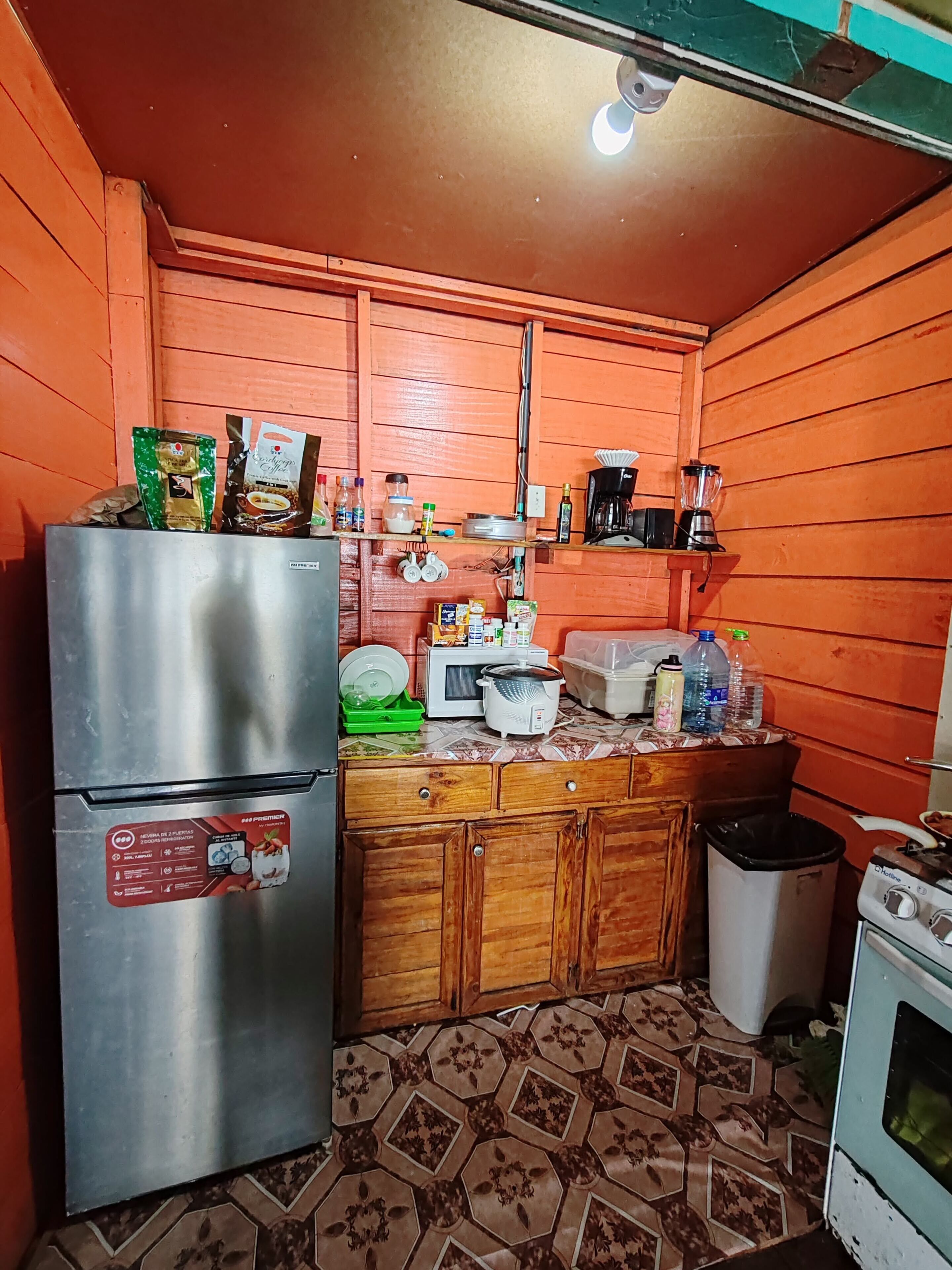 Una cocina compacta con un refrigerador de acero inoxidable, un microondas y una estufa.