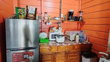 Una cocina compacta con un refrigerador de acero inoxidable, un microondas y una estufa.