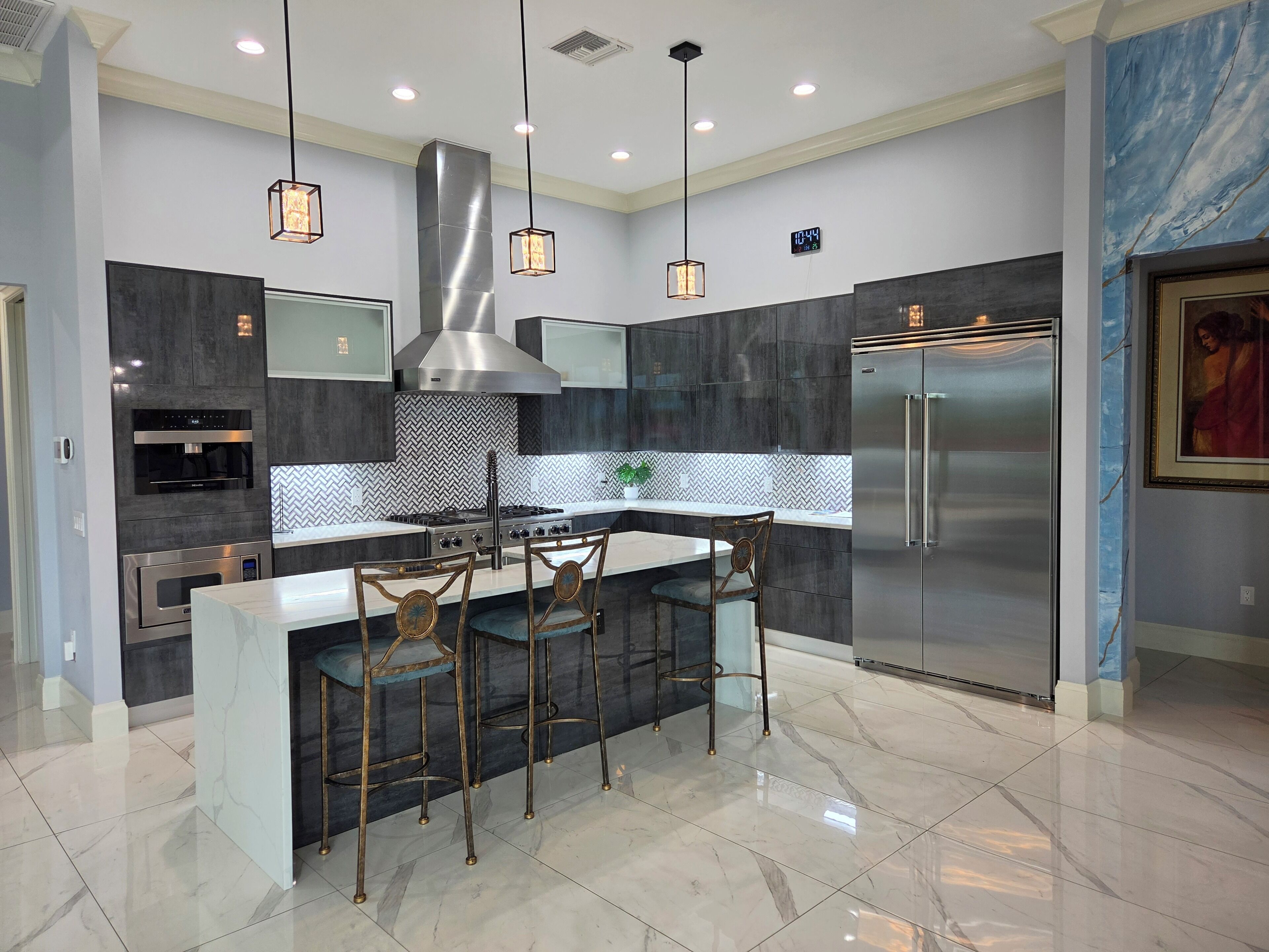 A modern kitchen with a central island, stainless steel appliances, and pendant lighting.