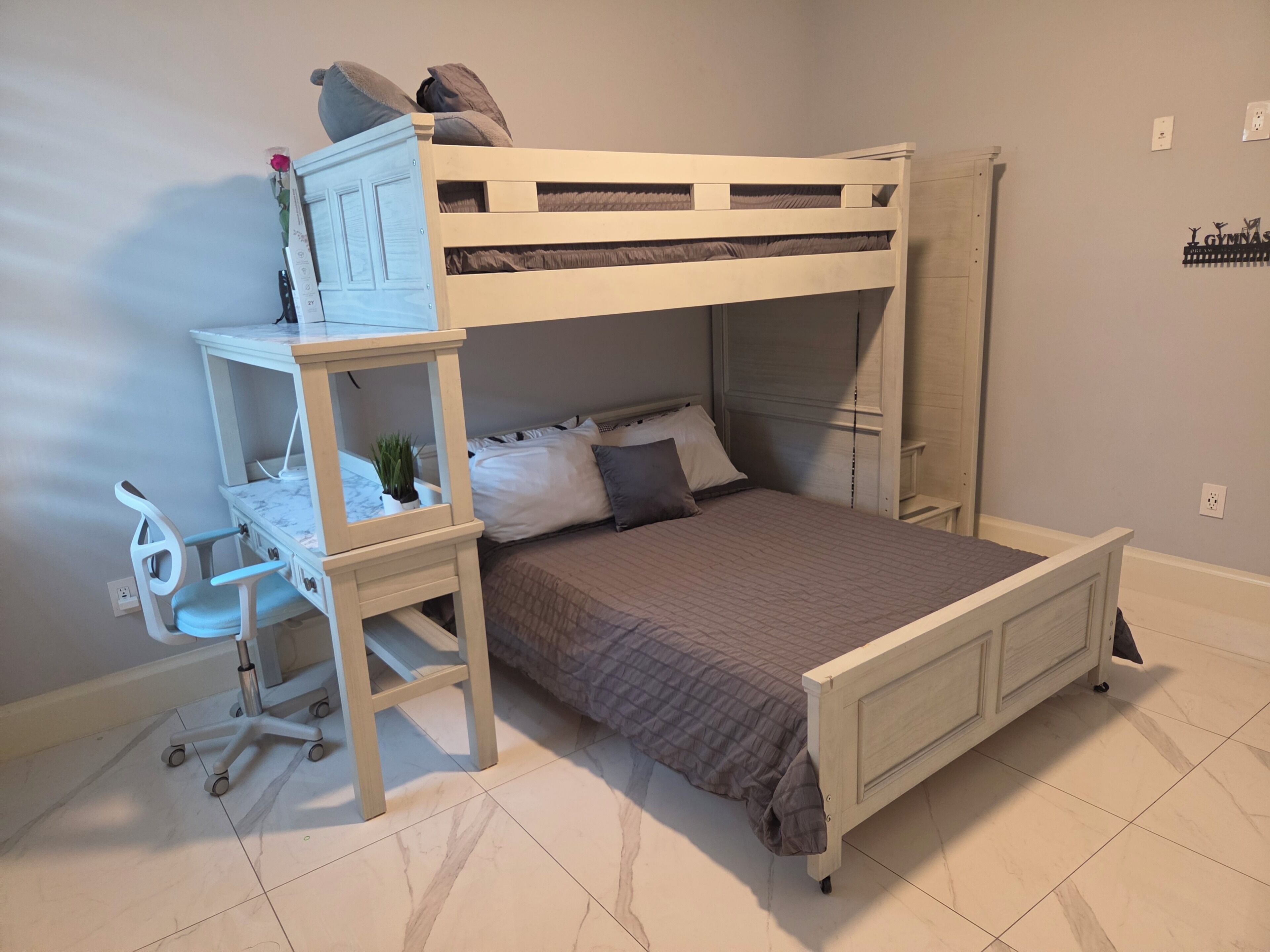 A bunk bed with a desk and chair, a small plant, and a wall decoration.