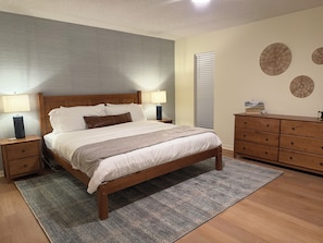A bedroom with a wooden bed, two bedside tables, a dresser, and decorative wall art.