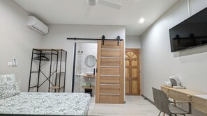 A bedroom with a bed, a desk, a chair, a wardrobe, and a TV mounted on the wall. - Accommodation, 12 min. from the lagoon, spa, air-conditioned, sleeps 4, 3 terraces, parking (Saint-Pierre)