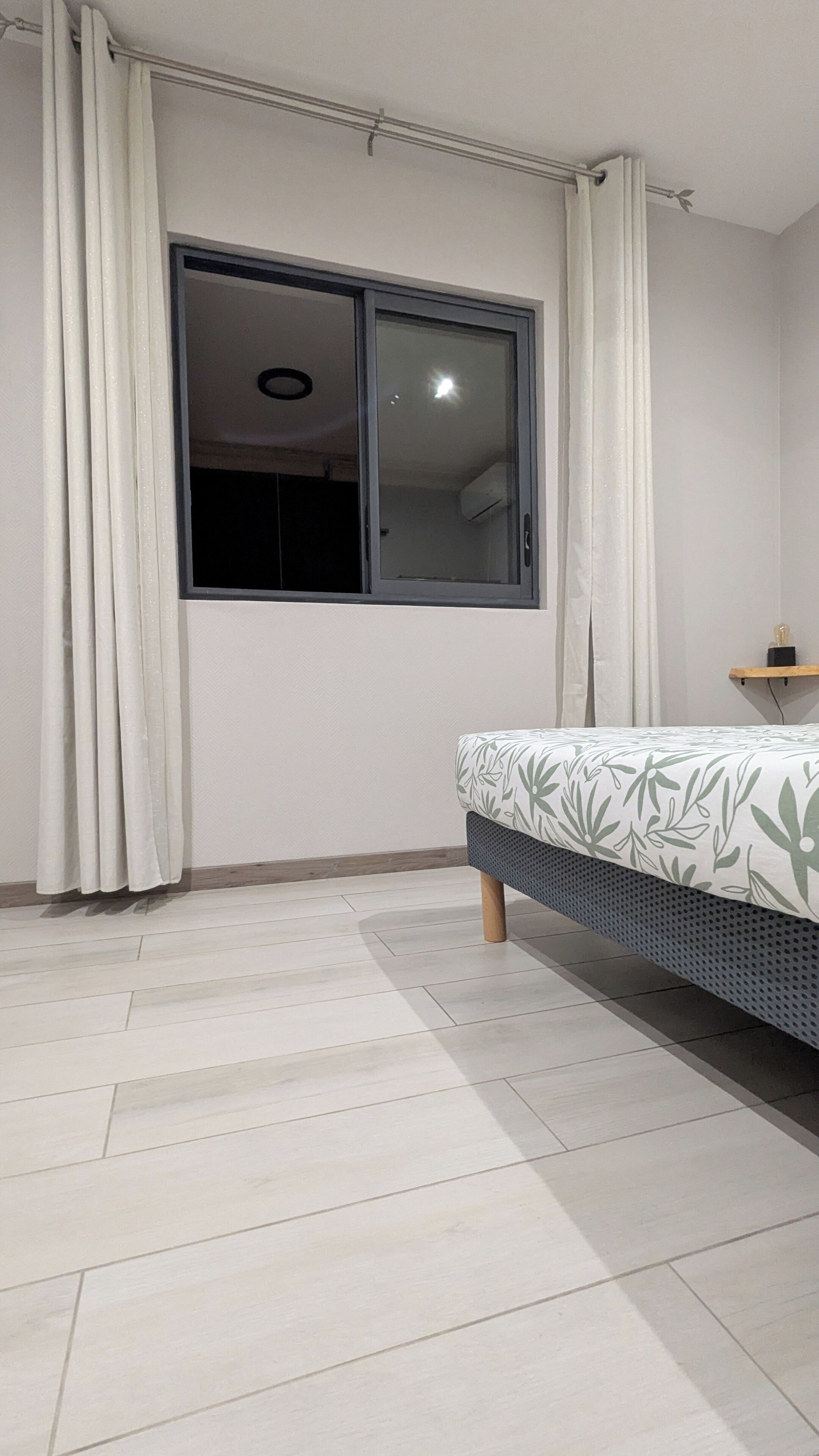 A bedroom with a bed, a window, and a ceiling fan.