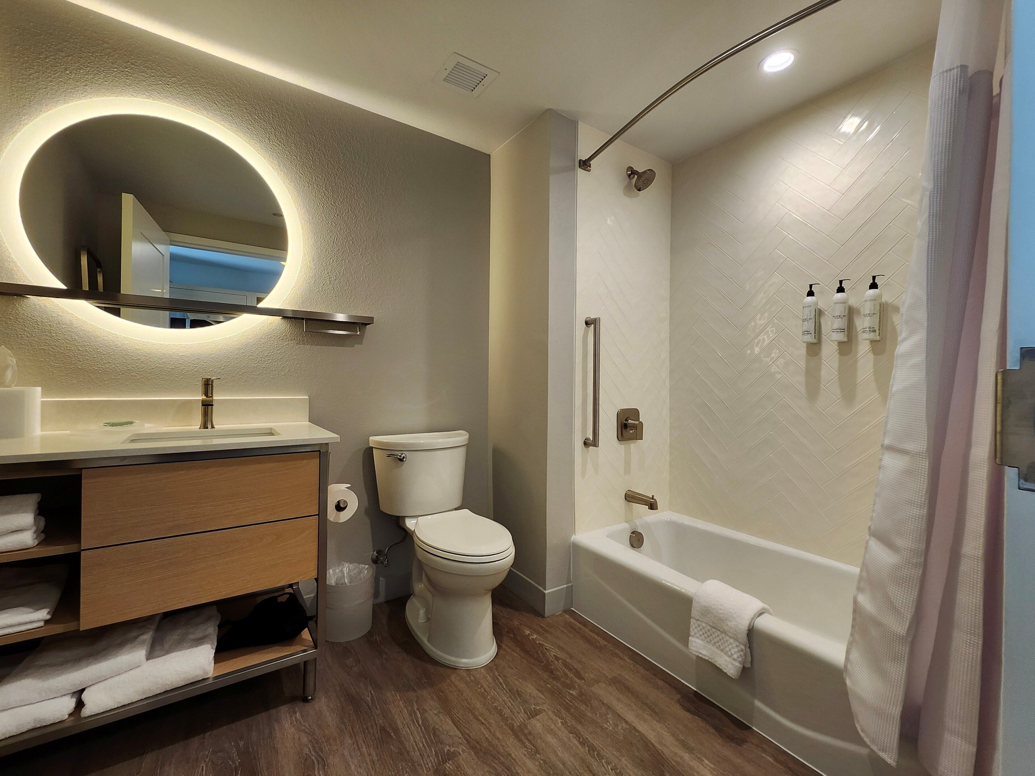 A modern bathroom with a toilet, sink, vanity, and a walk-in shower.