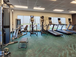 A gym with treadmills, elliptical machines, and weightlifting equipment. - Towneplace Suites By Marriott Burnet (Burnet)