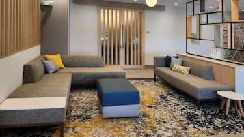 A modern living room with a sectional sofa, ottoman, and a small round table.