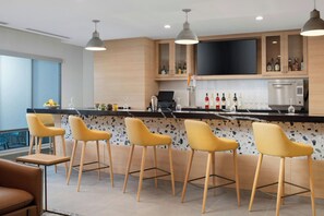 A modern kitchen with a bar area, bar stools, a flat-screen TV, and a wine bottle rack.