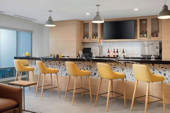 Une cuisine moderne dotée d’un coin bar, de tabourets de bar, d’un téléviseur à écran plat et d’un porte-bouteilles à vin.