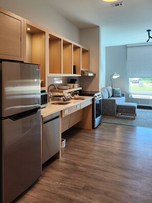 A modern kitchen with wooden cabinets, a stainless steel refrigerator, and a built-in oven.