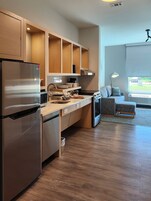 Una cocina moderna con armarios de madera, un refrigerador de acero inoxidable y un horno empotrado.