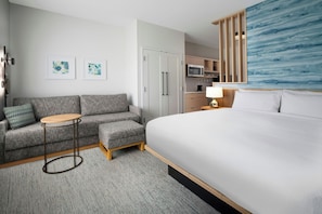 Una habitación de hotel con cama, sofá, una mesita, microondas y armario.