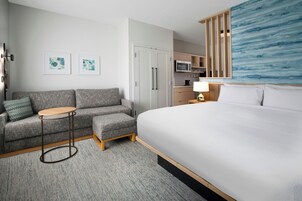Una habitación de hotel con cama, sofá, una mesita, microondas y armario.