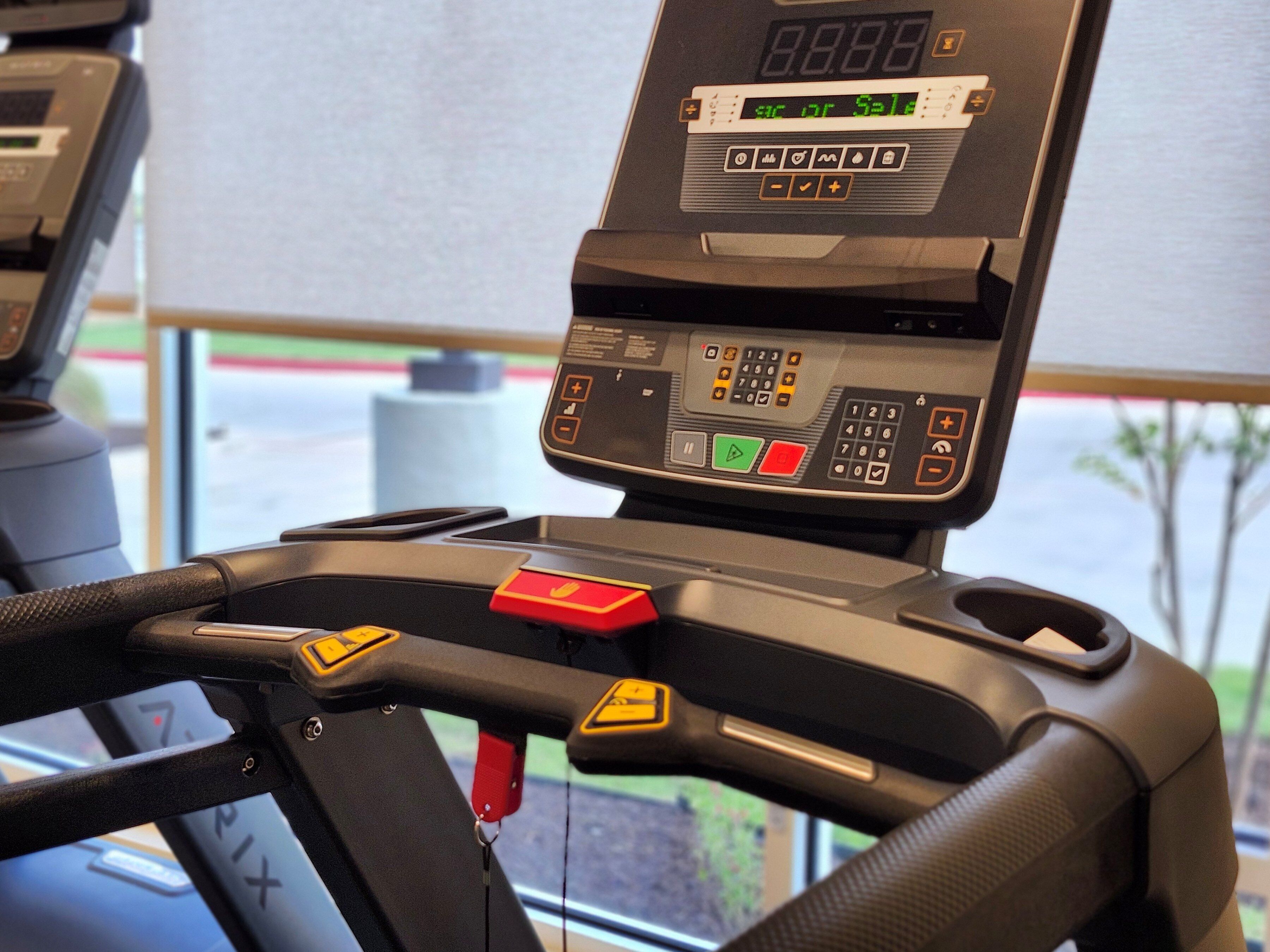A treadmill with a digital display, control panel, and safety features.
