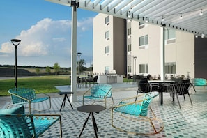 Un patio al aire libre con mobiliario, una parrilla y vistas a un edificio.