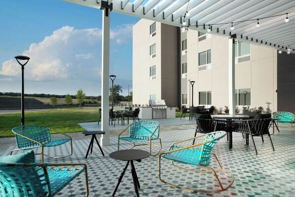 An outdoor patio area with seating, a grill, and a view of a building.