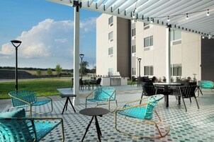 Un patio al aire libre con mobiliario, una parrilla y vistas a un edificio.