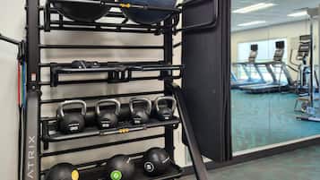 A gym with a rack holding various exercise equipment, including kettlebells and medicine balls.
