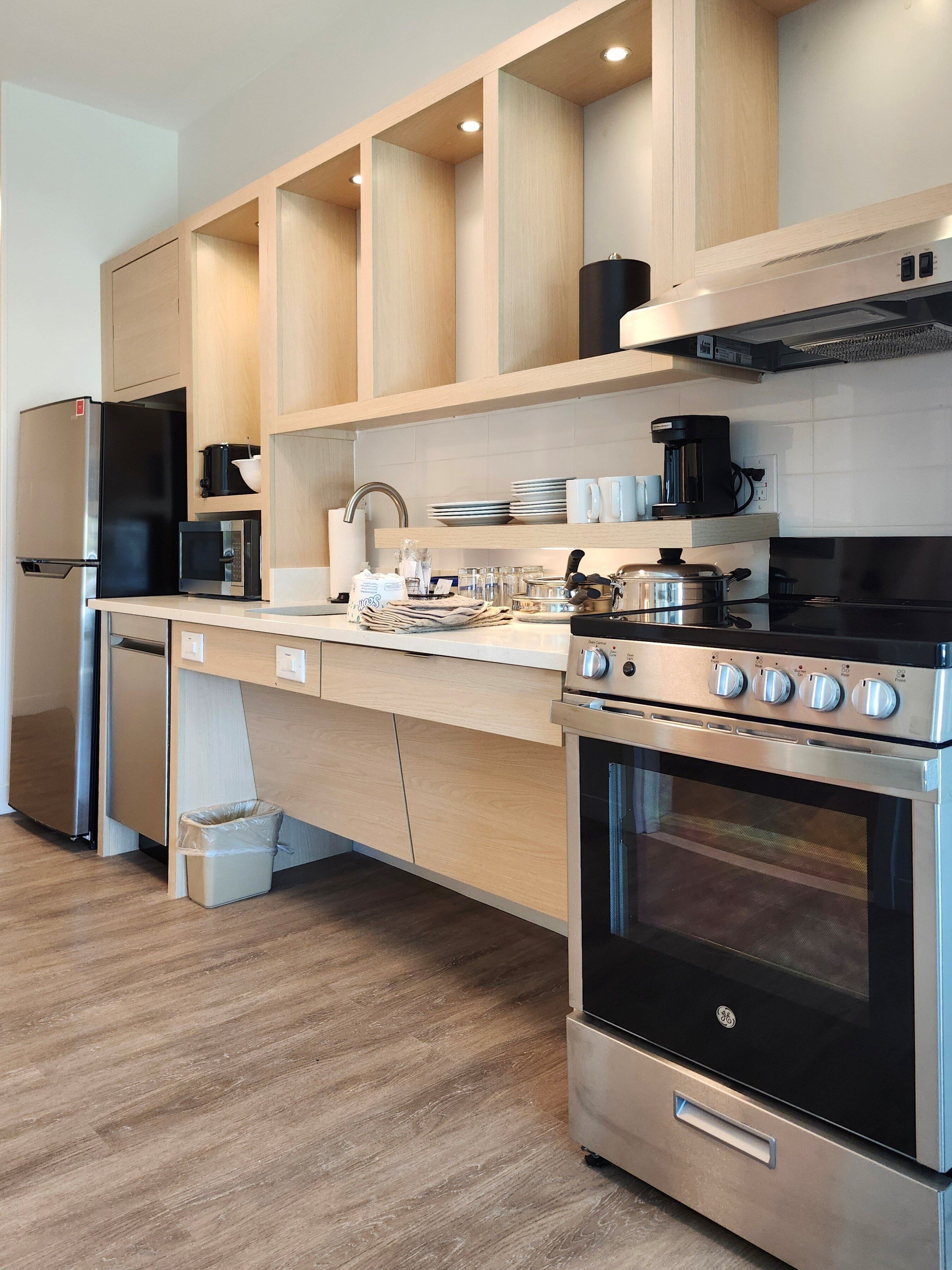 A modern kitchen with a stainless steel refrigerator, microwave, and oven, wooden cabinets, and a countertop with various kitchen items.
