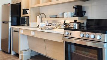 A modern kitchen with a stainless steel refrigerator, microwave, and oven, wooden cabinets, and a countertop with various kitchen items.