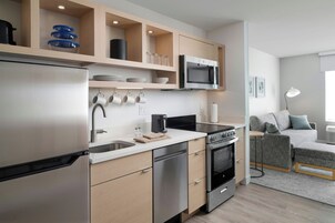 A modern kitchen with built-in appliances, a dining area with a sofa, and a small table.