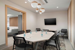 A conference room with a large table, chairs, water bottles, and a flat-screen TV on the wall.