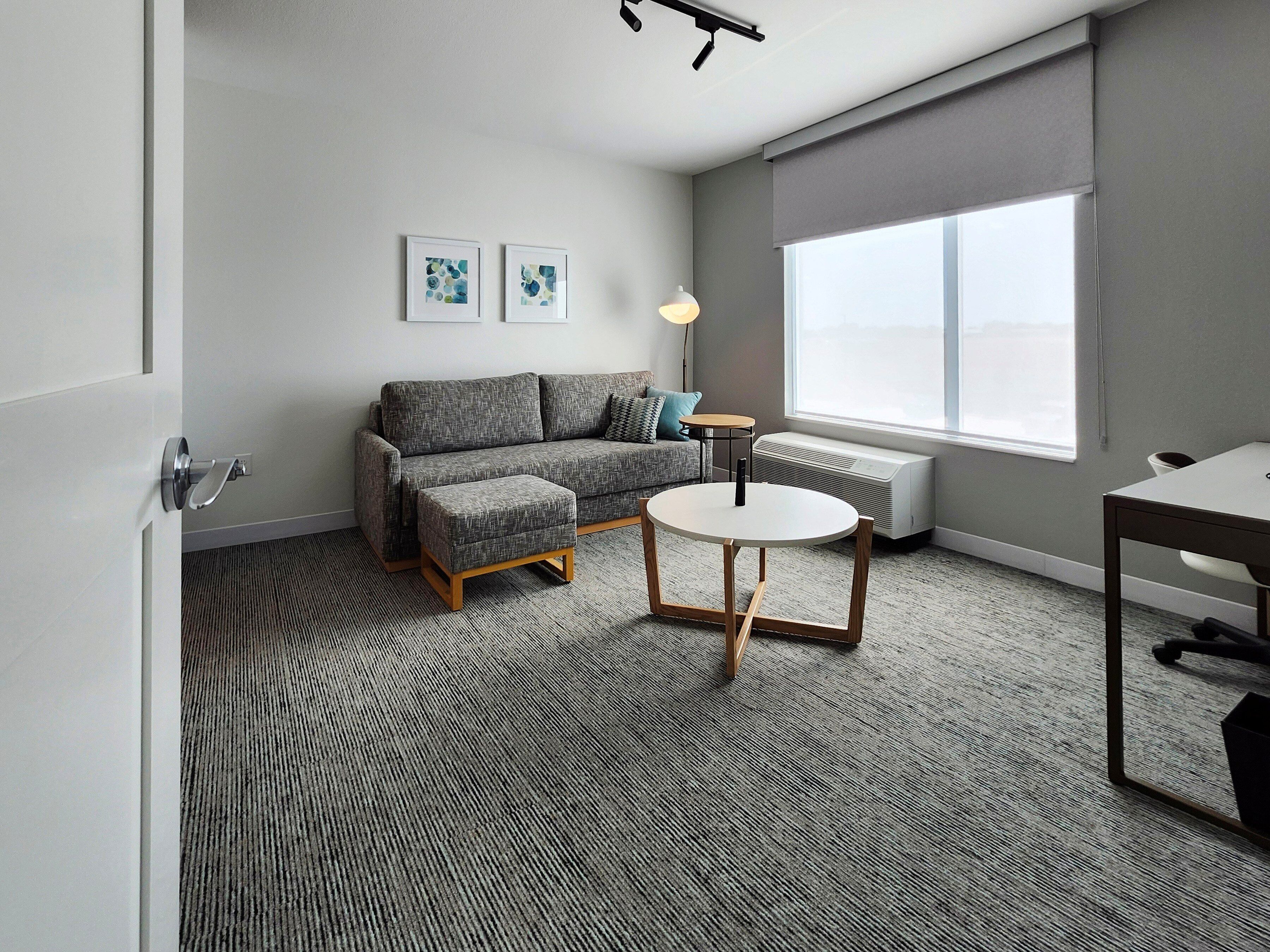 A modern living room with a grey sofa, a round table, and a radiator.