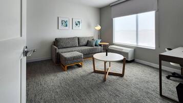 A modern living room with a grey sofa, a round table, and a radiator.