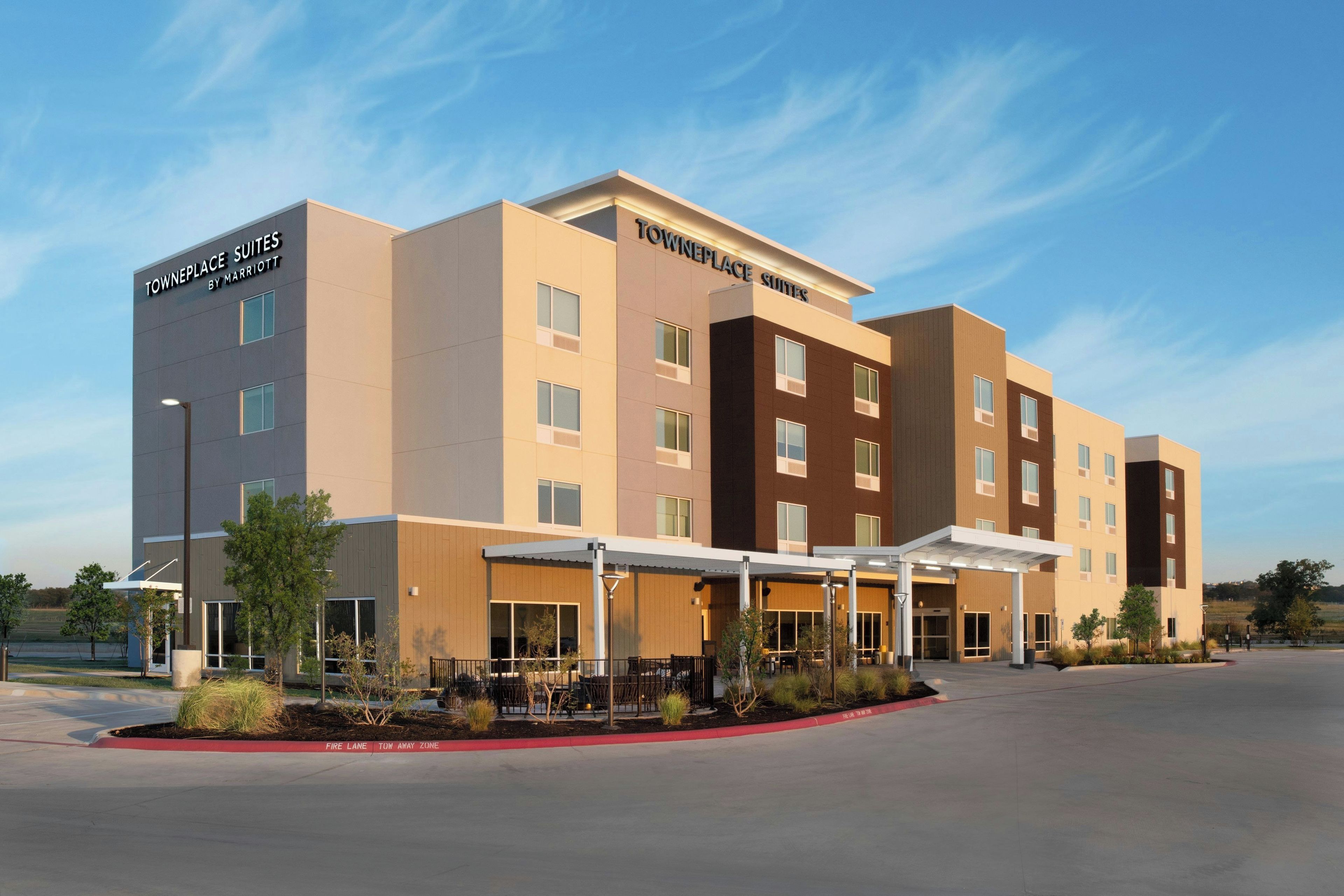 A Towneplace Suites by Marriott hotel with a modern design, multiple floors, and a covered outdoor area.