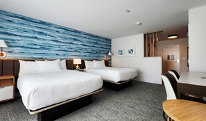Une chambre d’hôtel avec deux lits, un bureau et une chaise.