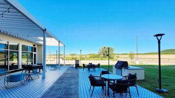 An outdoor patio area with tables and chairs, a covered seating area, and a view of the landscape.