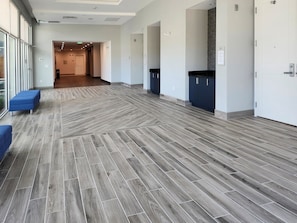 A hallway with a herringbone floor pattern, blue seating, and a door at the end. - Towneplace Suites By Marriott Burnet (Burnet)