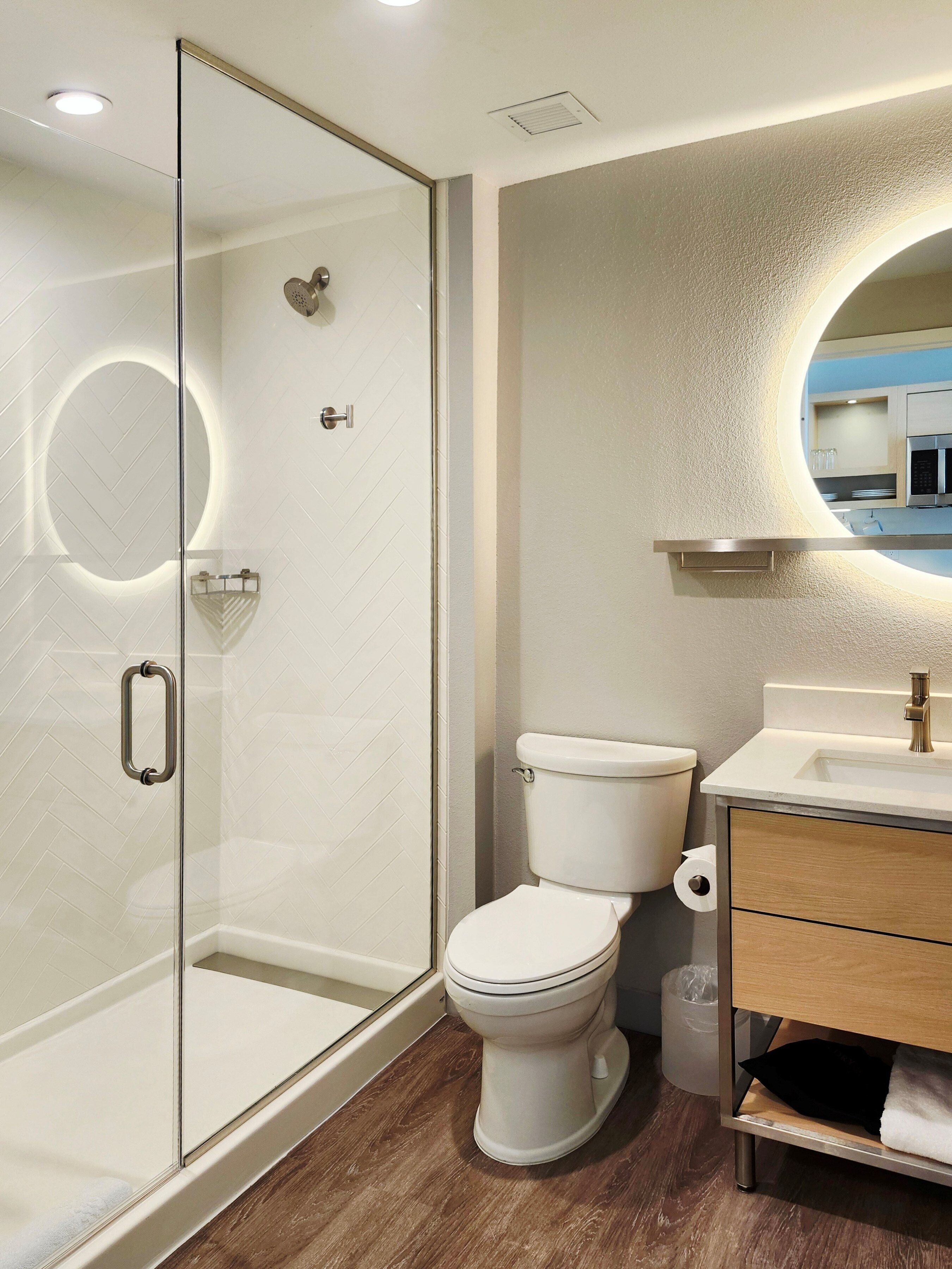 Une salle de bain moderne avec une douche à parois de verre, des toilettes et un meuble-lavabo avec un miroir.