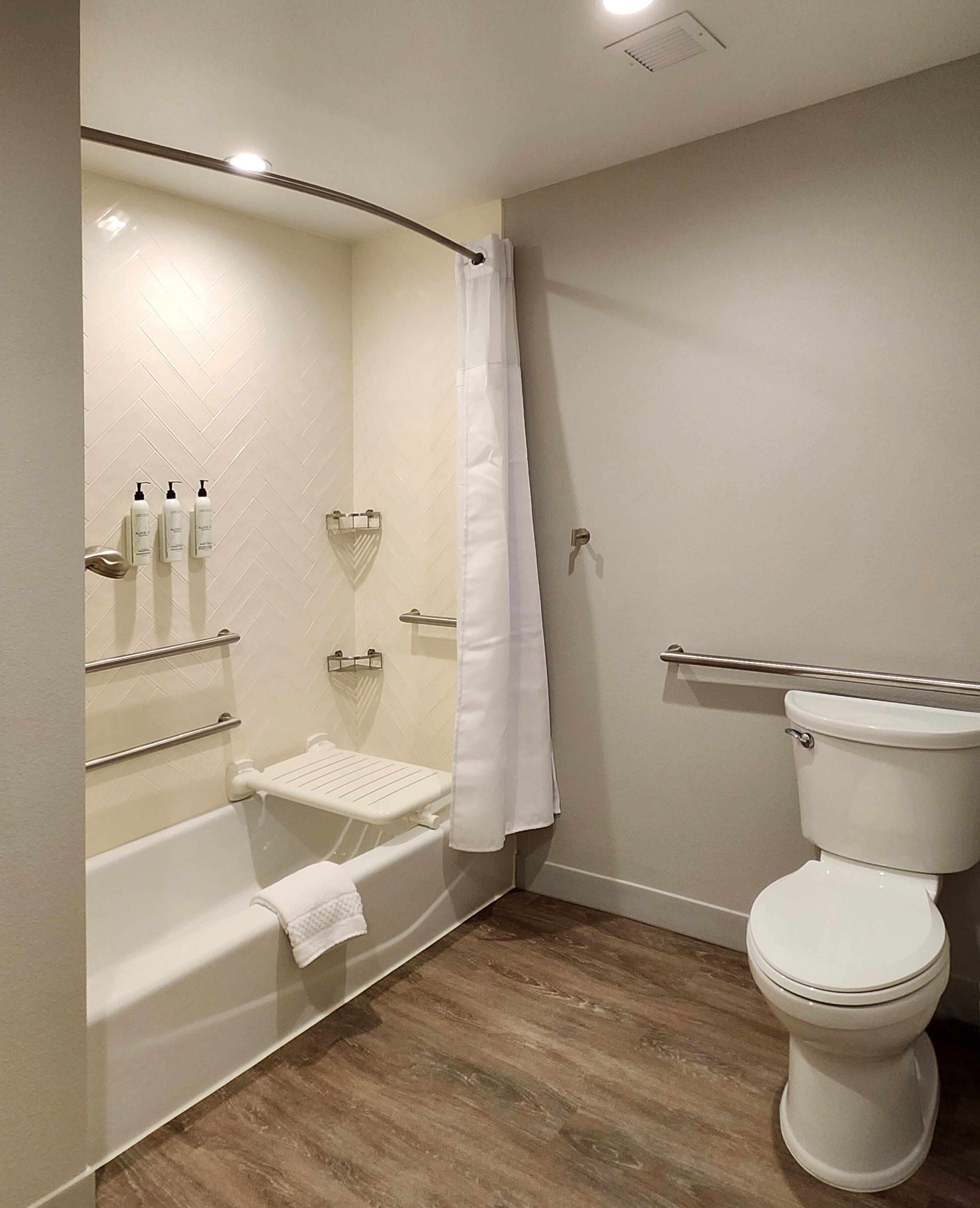A modern bathroom with a bathtub, toilet, and shower area.
