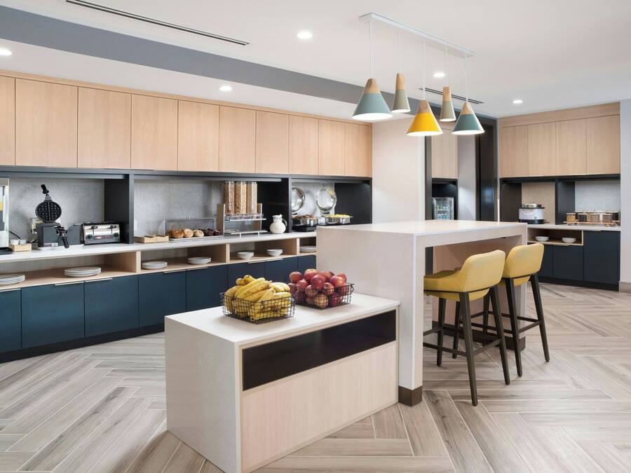 Une cuisine moderne dotée d’un îlot central, de tabourets de bar et d’un appareil à gaufres.